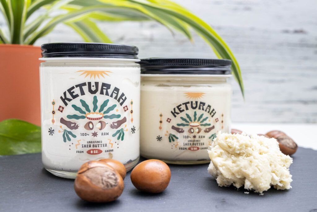 Natural skincare products displayed with shea seeds and a sea sponge on a light surface, featuring jars of shea butter labeled ‘Naturals.’