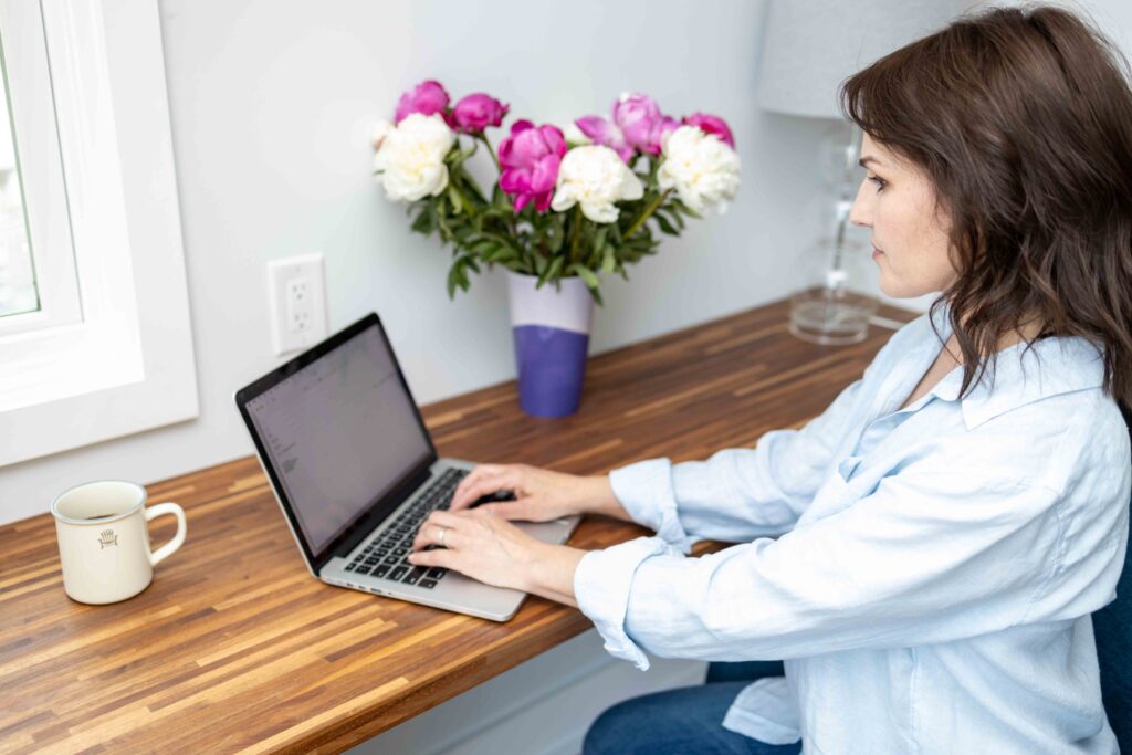 woman in blue blouse typing on a laptop