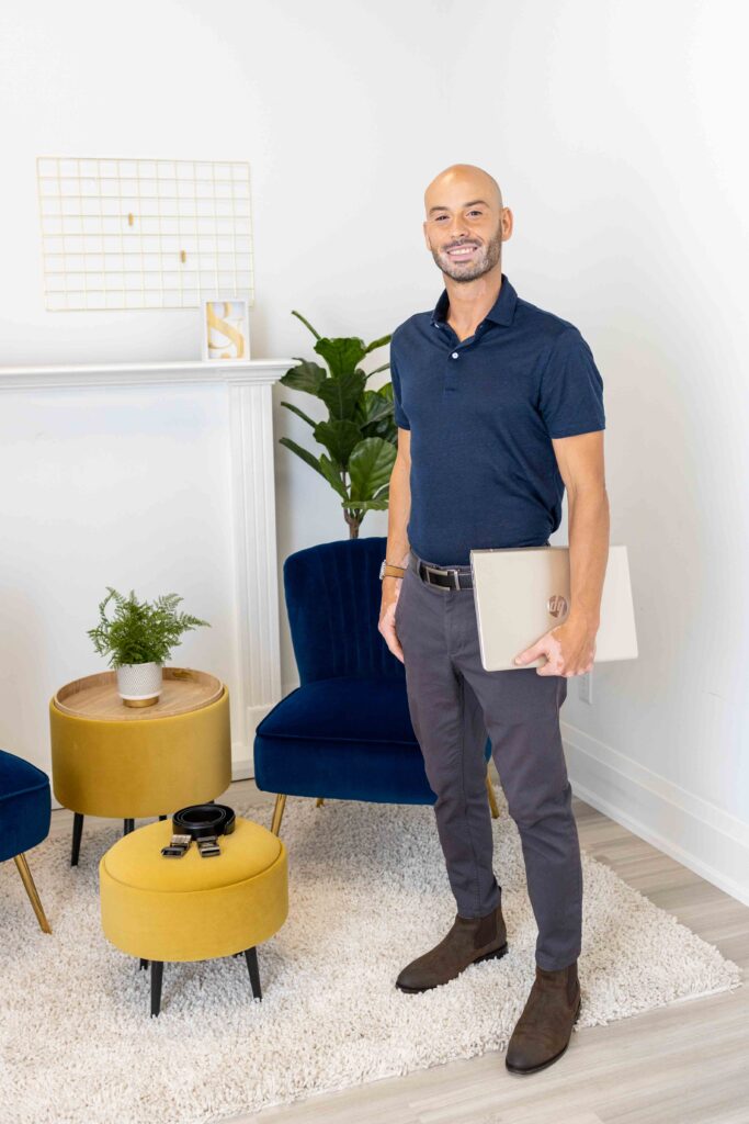 Branding portrait of a man standing confidently in a blue shirt holding a notebook — Burlington studio session.