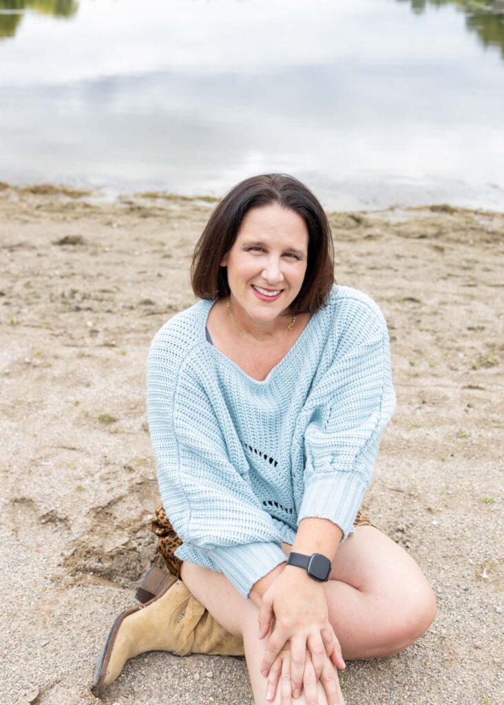 Personal branding portrait of Amy Tokic sitting on a sandy beach in a light blue sweater — photographed by Marta Raptis in Mississauga.