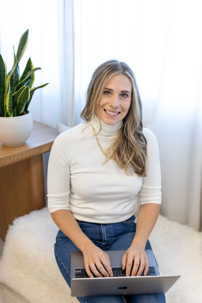 Lifestyle branding portrait of a woman in a white turtleneck seated on a cozy chair with plants in the background — Burlington studio session by Marta Raptis.