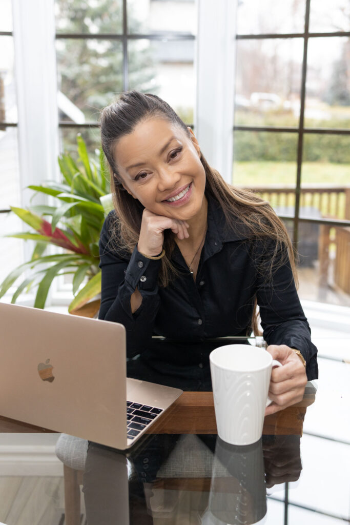 Woman smiling at her laptop with coffee mug in hand, natural light branding photo for creative professionals.