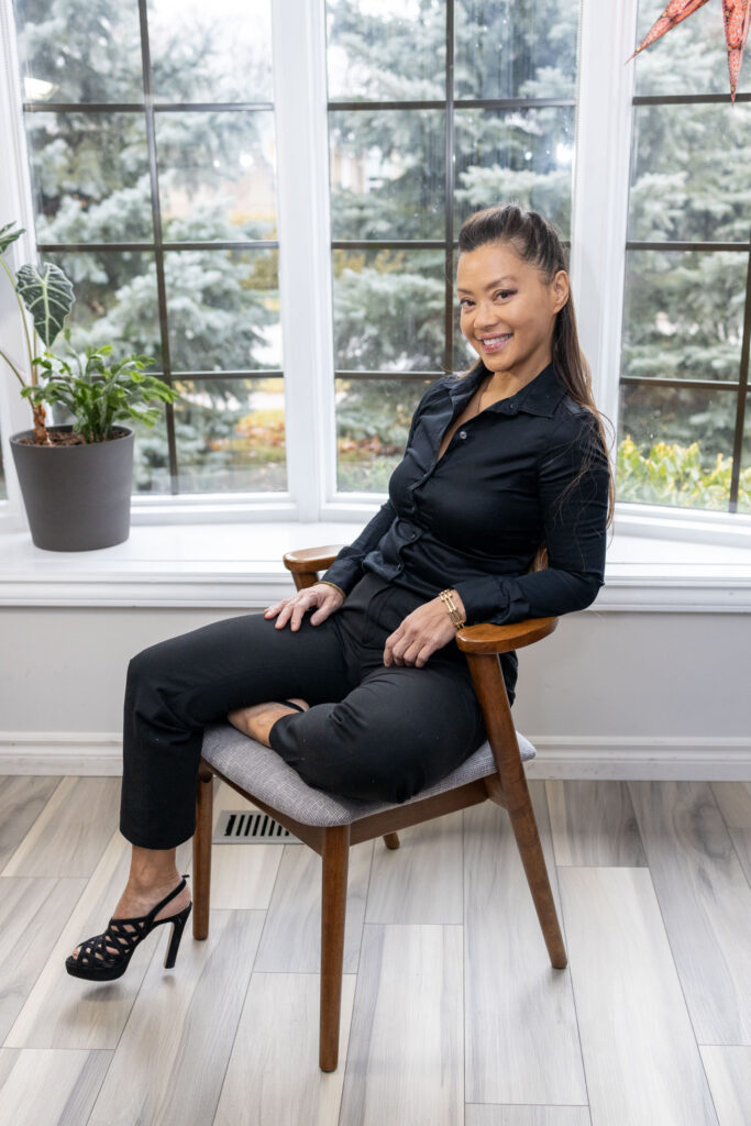 Confident branding portrait of a woman in a black outfit sitting on a chair — Burlington branding session.
