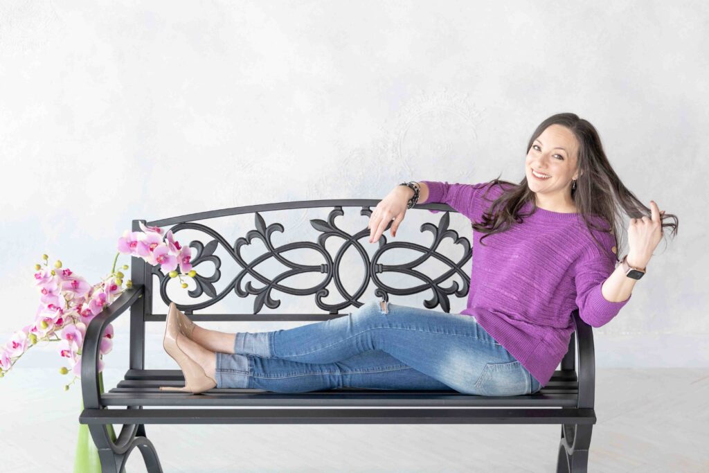 smiling woman sitting on a bench with purple flowers