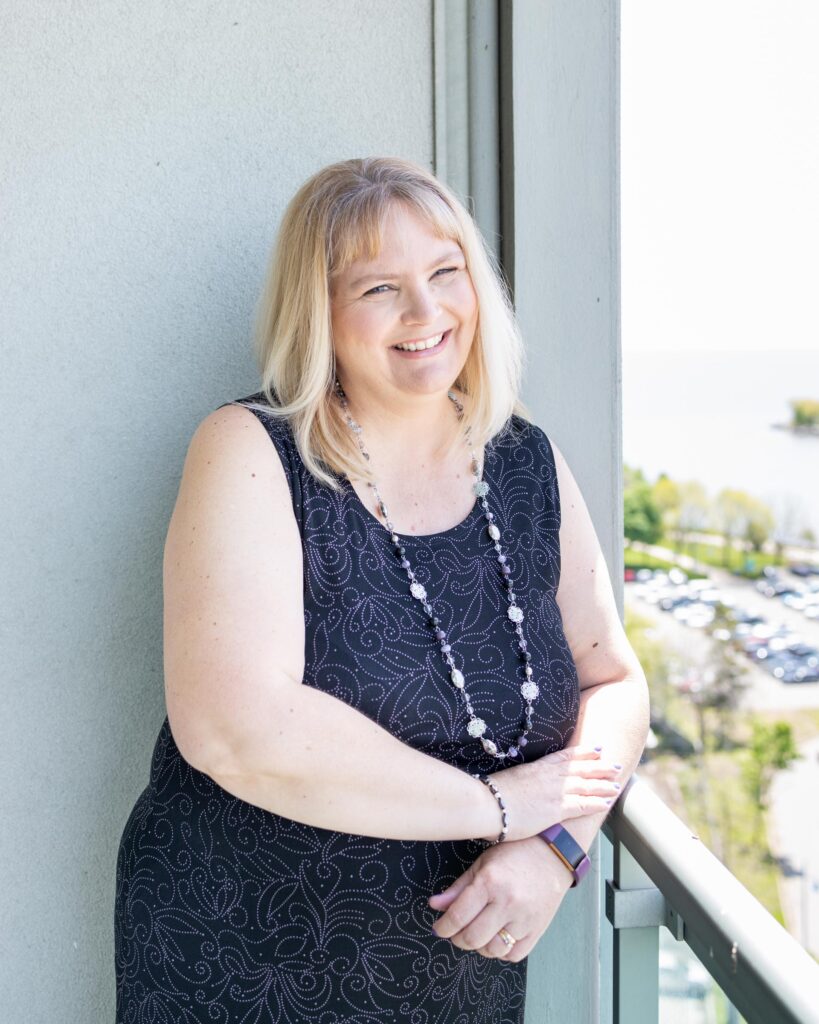 Personal branding portrait of a woman sitting near a bright window with lake view — photographed by Marta Raptis in Oakville.
