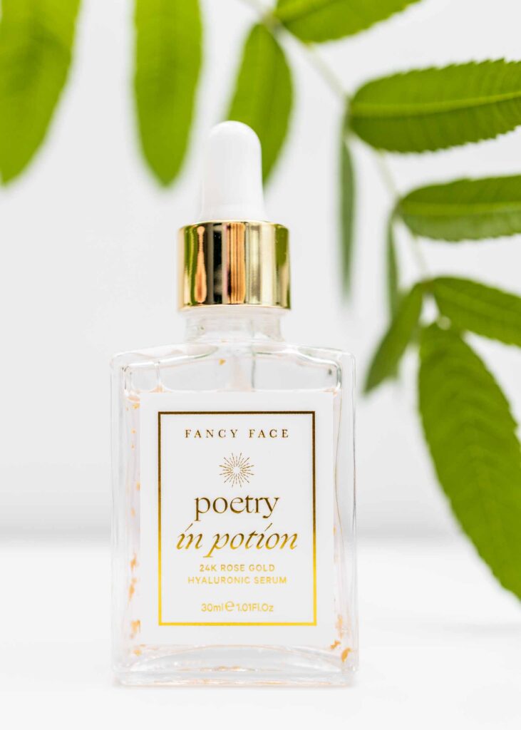 Luxury skincare product image of Fancy Face Poetry in Potion serum bottle with gold dropper and green leaves.