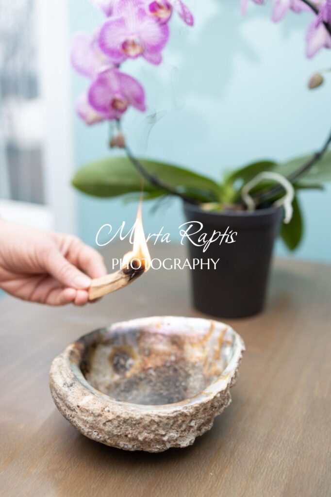 Hand holding a spoon near a potted orchid, soft light wellness stock photo for mindful brands.