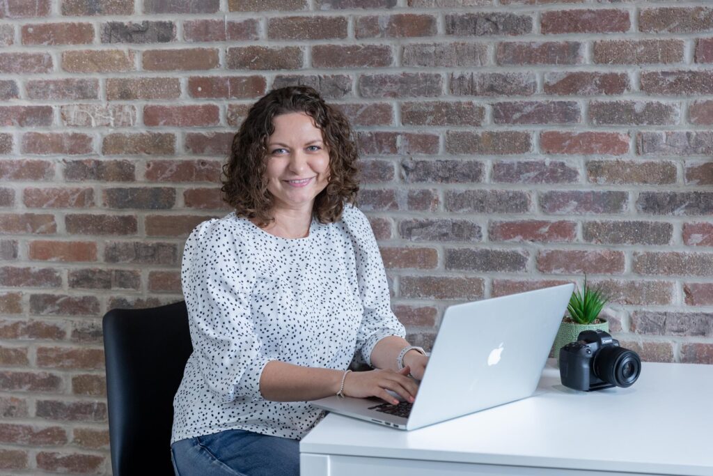 Marta Raptis branding photographer working on laptop with camera on desk in bright studio