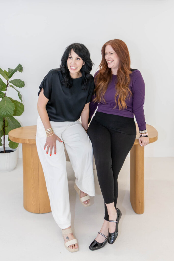 Samara Foisy and Allison Jorgens seated together smiling, photographed for Qwiky Wellness branding shoot by Marta Raptis.