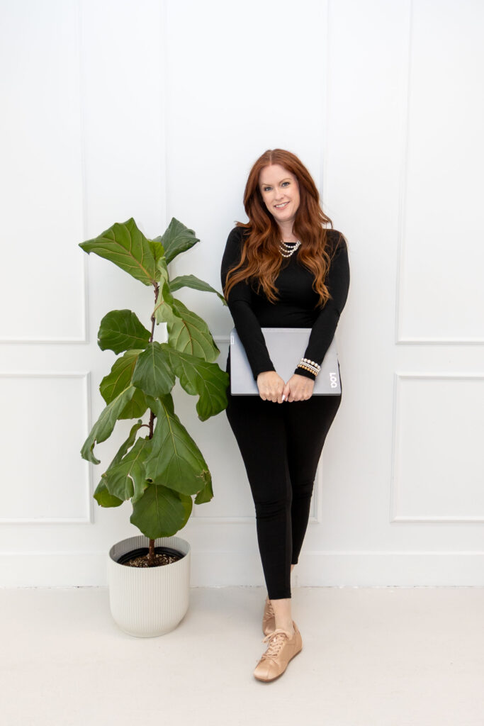 Allison Jorgens standing beside a tall plant holding notebook, photographed for Qwiky Wellness branding shoot by Marta Raptis.