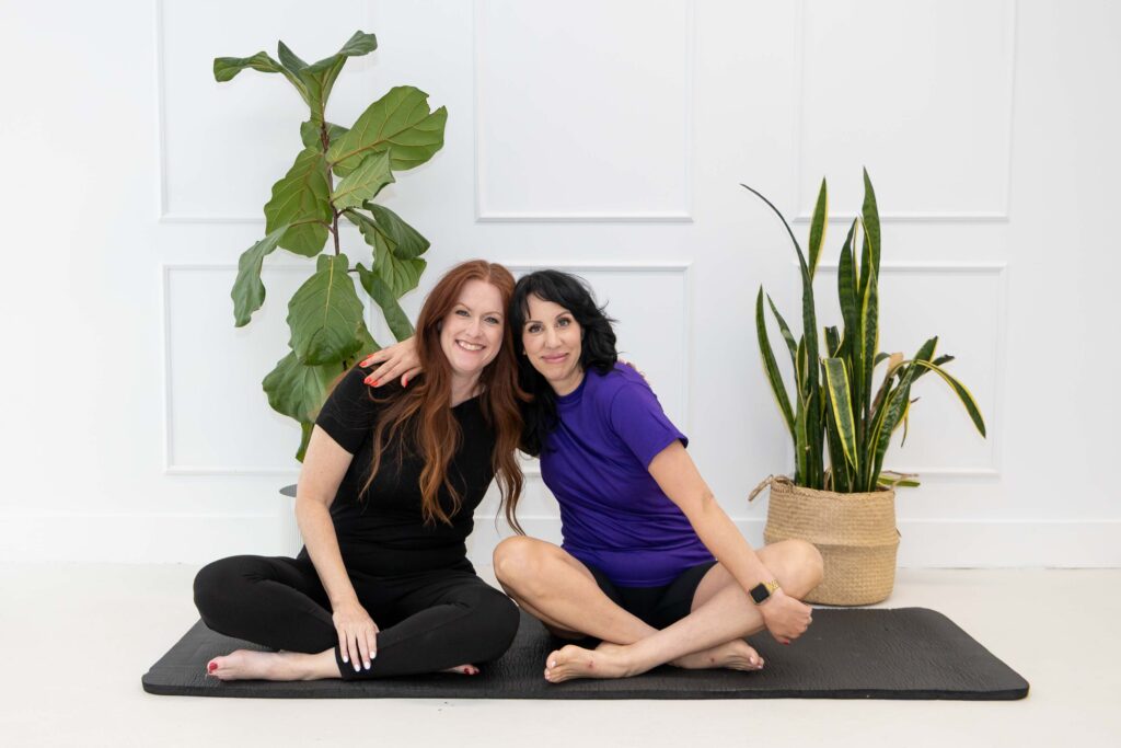 Samara Foisy and Allison Jorgens seated cross‑legged on yoga mats with plants behind them, photographed for Qwiky Wellness branding shoot by Marta Raptis.