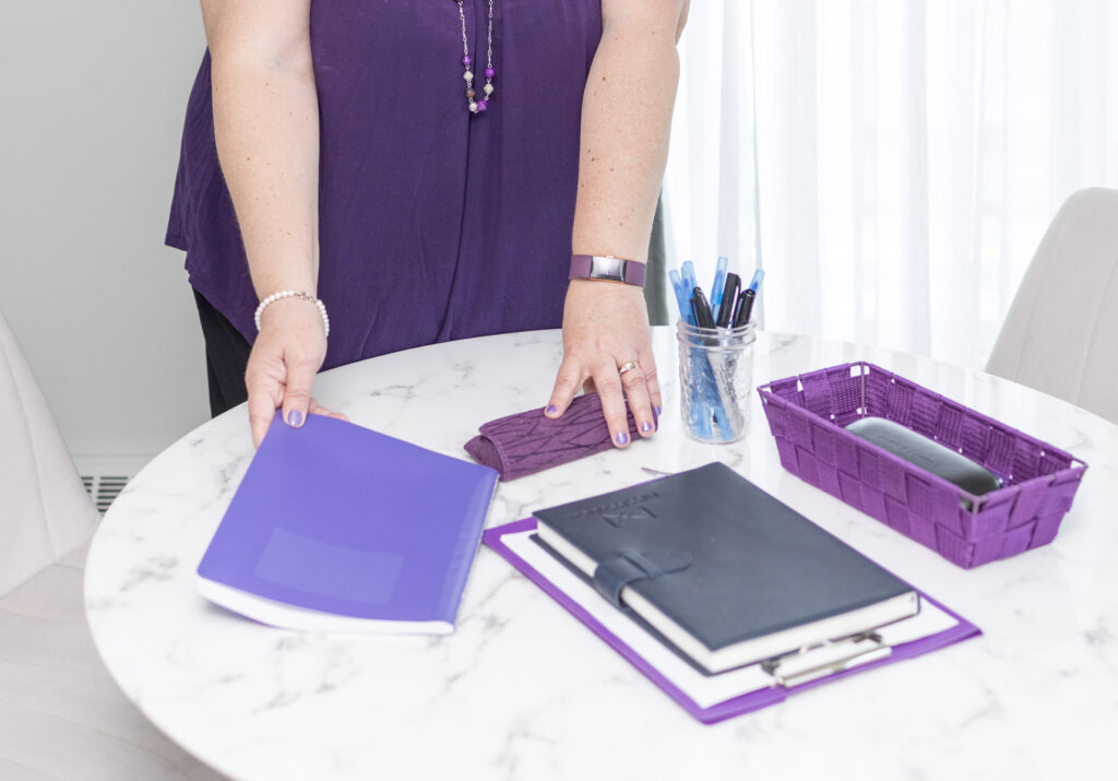 Woman standing behind a table with creative tools, smiling confidently in a bright studio — representing professionalism and authenticity in branding for creatives.